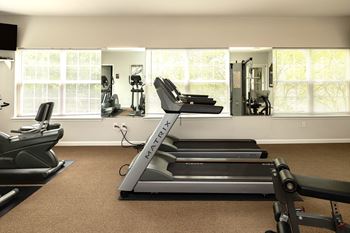 A home gym with a treadmill, elliptical machines, and other exercise equipment.
